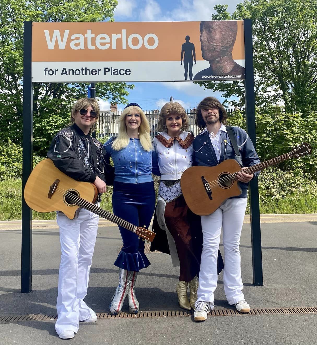 Masters Of The Scene ABBA tribute band in front of Waterloo station sign